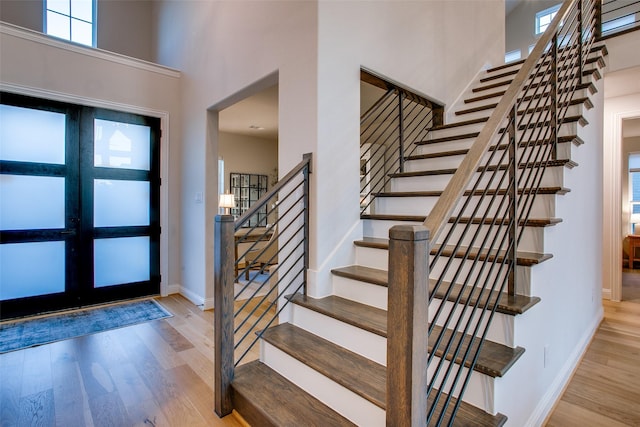 entryway with french doors, a high ceiling, and light hardwood / wood-style flooring