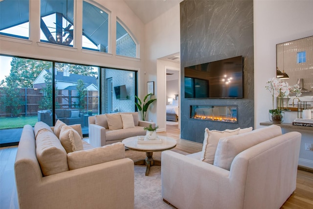 living room featuring light wood-type flooring, high vaulted ceiling, and a premium fireplace