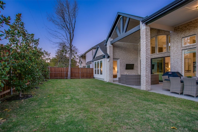 yard at dusk featuring an outdoor living space, ceiling fan, and a patio