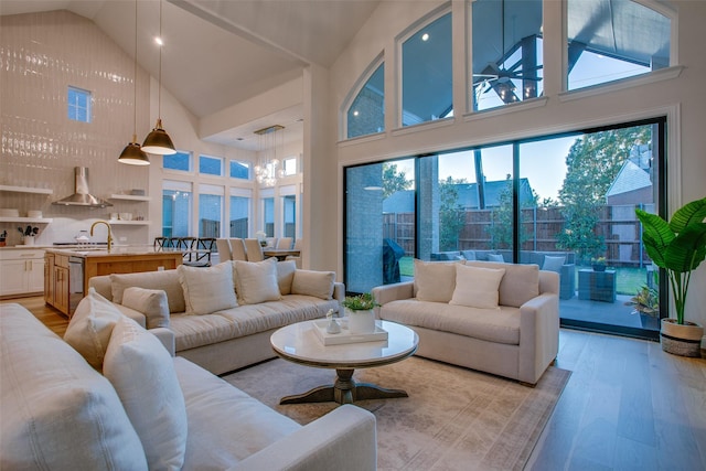 living room with light hardwood / wood-style flooring, high vaulted ceiling, and an inviting chandelier