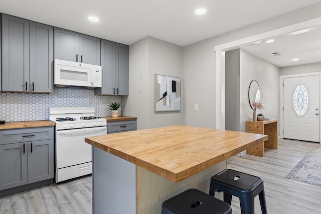 kitchen with gray cabinets, white appliances, light hardwood / wood-style flooring, and wooden counters