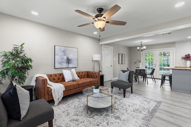 living room featuring french doors, light hardwood / wood-style flooring, and ceiling fan with notable chandelier