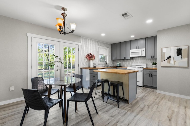 dining room featuring a chandelier, french doors, light hardwood / wood-style flooring, and sink