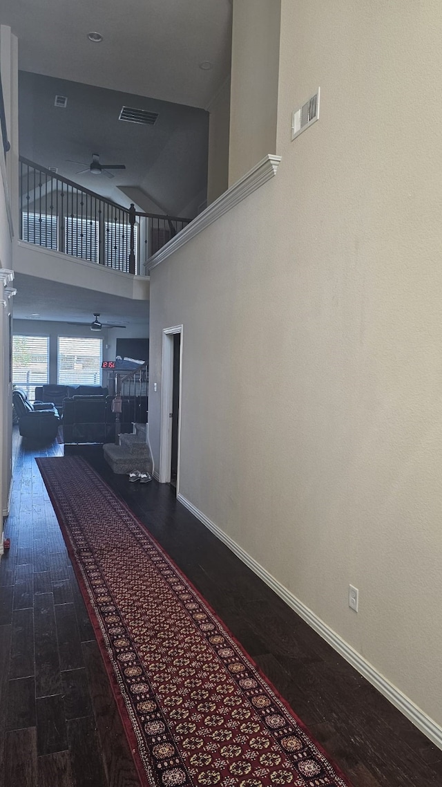 hallway featuring wood-type flooring and a towering ceiling