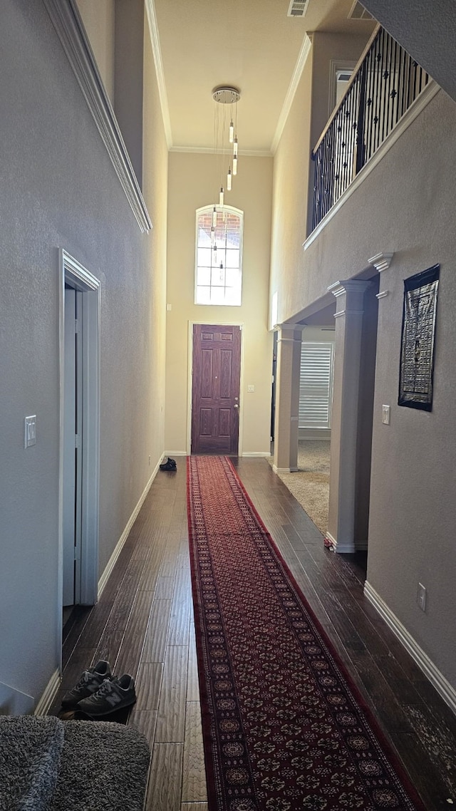 interior space featuring ornate columns, crown molding, dark hardwood / wood-style floors, and a high ceiling