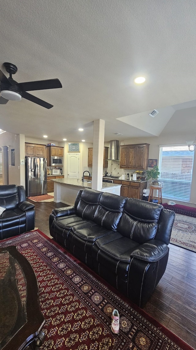 living room with ceiling fan, sink, dark wood-type flooring, and a textured ceiling