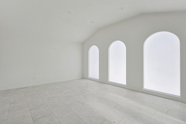 empty room featuring lofted ceiling and light tile patterned floors