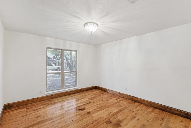 unfurnished room featuring light hardwood / wood-style floors and a textured ceiling