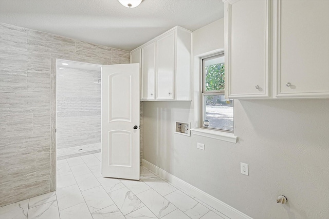 clothes washing area with cabinets, washer hookup, and a textured ceiling