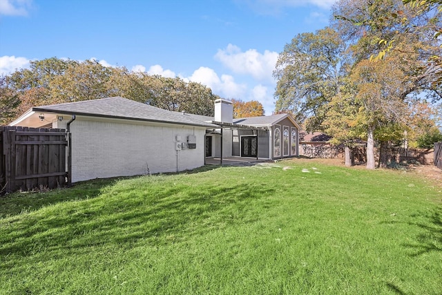 back of property with a sunroom and a yard