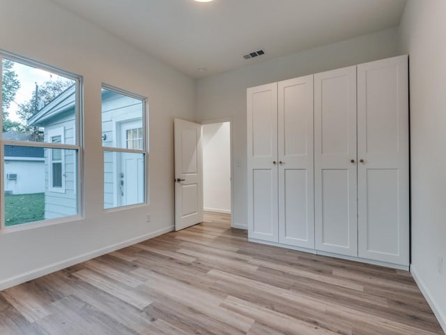 unfurnished bedroom with light hardwood / wood-style floors and a closet