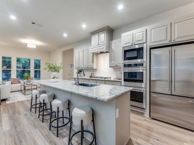 kitchen featuring appliances with stainless steel finishes, a kitchen island with sink, a breakfast bar area, and sink