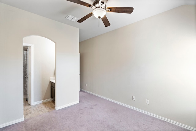 unfurnished bedroom with ensuite bath, ceiling fan, and light carpet