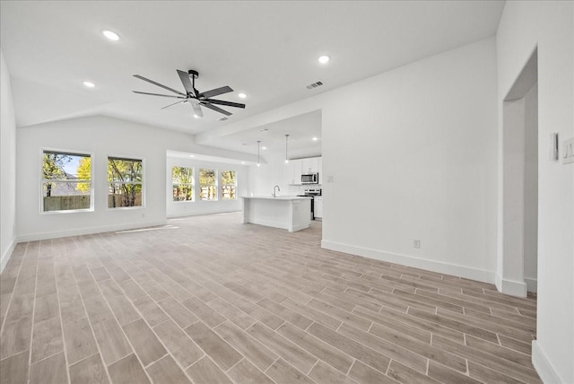 unfurnished living room featuring vaulted ceiling, ceiling fan, sink, and light wood-type flooring