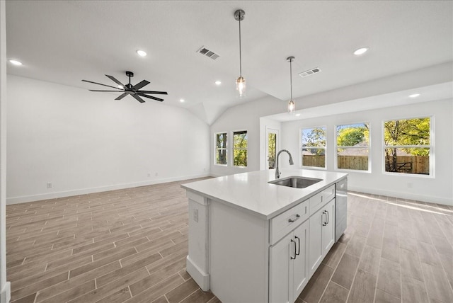 kitchen featuring pendant lighting, white cabinetry, dishwasher, sink, and a kitchen island with sink