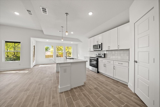 kitchen featuring white cabinetry, appliances with stainless steel finishes, sink, and a center island with sink