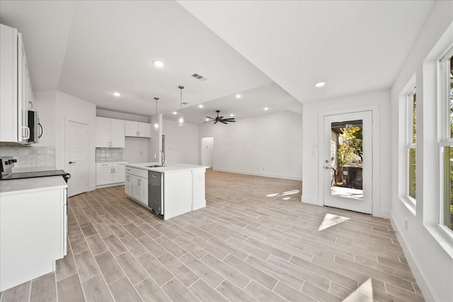 kitchen featuring pendant lighting, appliances with stainless steel finishes, a kitchen island with sink, white cabinets, and decorative backsplash