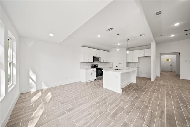 kitchen with sink, a kitchen island with sink, white cabinetry, stainless steel appliances, and decorative light fixtures