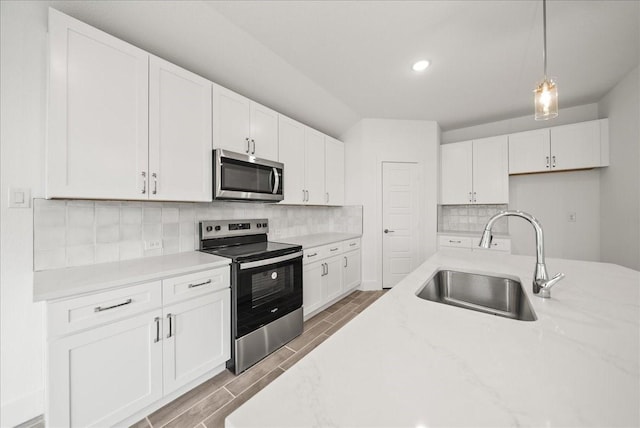 kitchen with white cabinetry, sink, decorative light fixtures, and stainless steel appliances