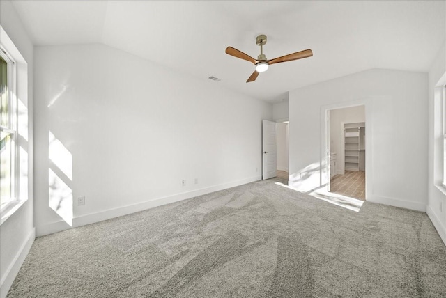 unfurnished bedroom featuring multiple windows, light colored carpet, and lofted ceiling