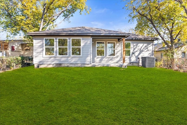 rear view of house featuring central AC and a yard