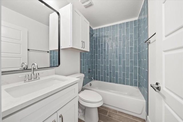 full bathroom featuring tiled shower / bath, vanity, a textured ceiling, and toilet