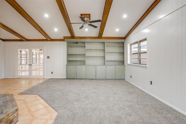 unfurnished living room with french doors, vaulted ceiling with beams, ceiling fan, and wood walls