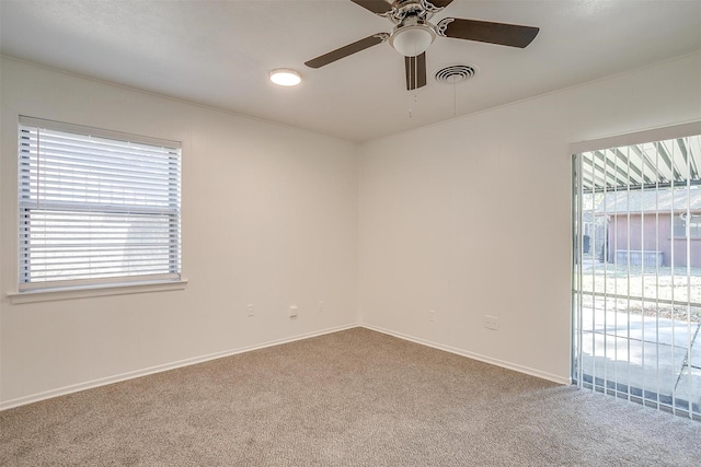 empty room featuring ceiling fan, plenty of natural light, and carpet floors