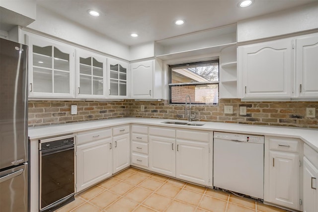 kitchen featuring white dishwasher, decorative backsplash, white cabinetry, and stainless steel refrigerator