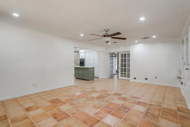 tiled empty room featuring ceiling fan and a textured ceiling