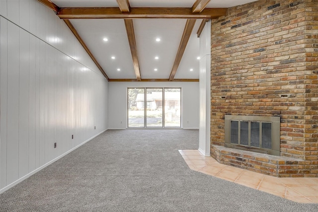 unfurnished living room featuring wood walls, lofted ceiling with beams, crown molding, a fireplace, and light colored carpet