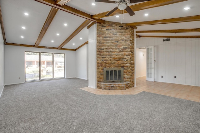 unfurnished living room with vaulted ceiling with beams, a fireplace, light colored carpet, and ceiling fan