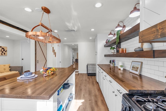 kitchen with white cabinetry, a barn door, backsplash, and wooden counters