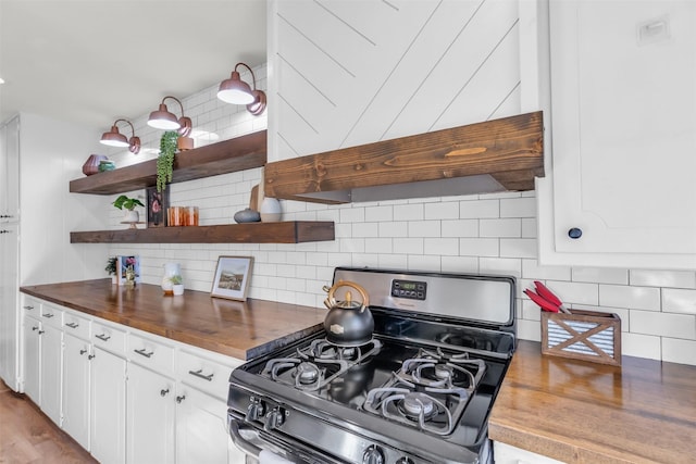 kitchen featuring premium range hood, stainless steel range with gas stovetop, white cabinets, and butcher block countertops