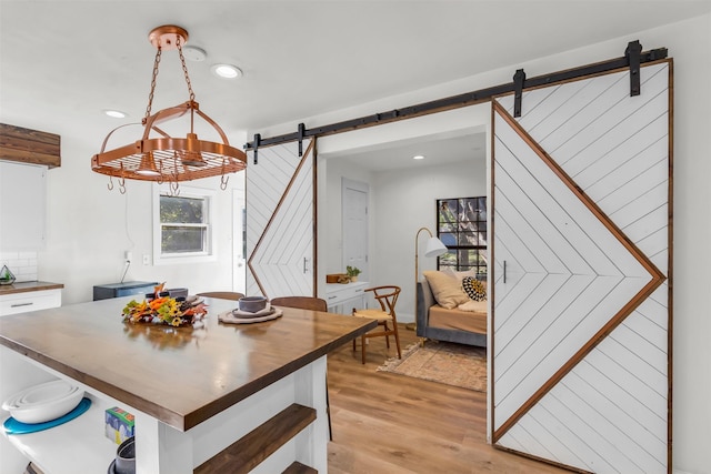 dining space with a barn door and light hardwood / wood-style floors