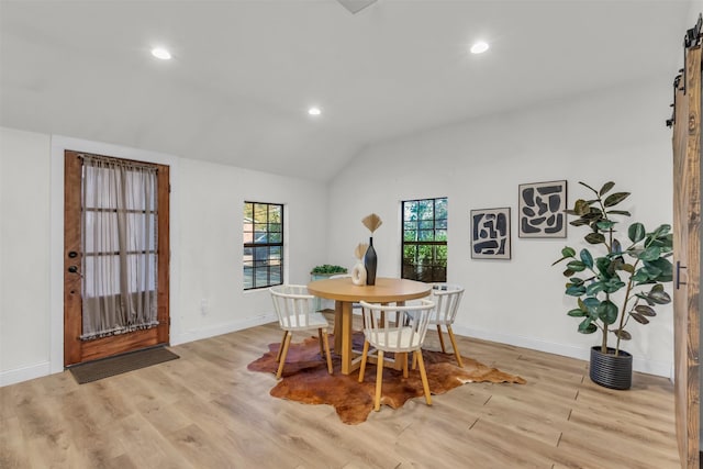 dining space with vaulted ceiling and light hardwood / wood-style flooring