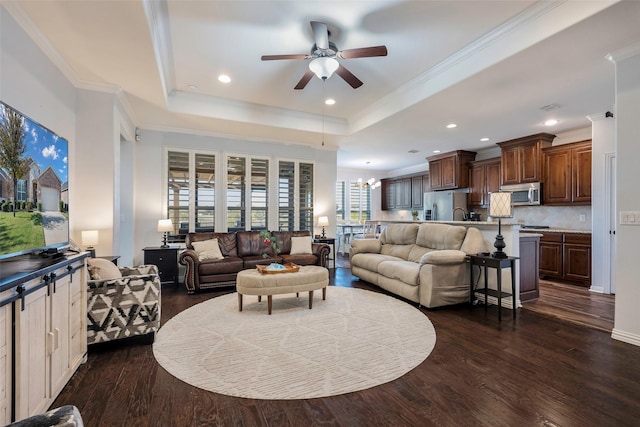 living room featuring a tray ceiling, ceiling fan with notable chandelier, ornamental molding, and dark hardwood / wood-style floors