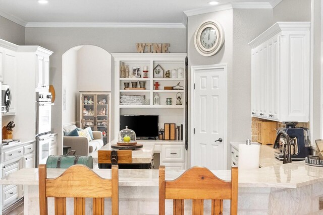 kitchen with dark wood-type flooring, white cabinetry, a kitchen breakfast bar, a center island, and decorative backsplash