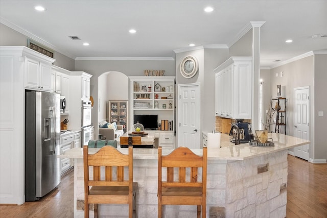 kitchen with stainless steel appliances, white cabinets, light wood-type flooring, and kitchen peninsula