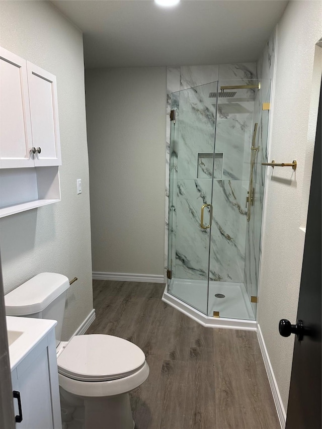 bathroom with wood-type flooring, toilet, a shower with shower door, and vanity