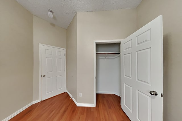 unfurnished bedroom featuring hardwood / wood-style flooring, a textured ceiling, and a closet