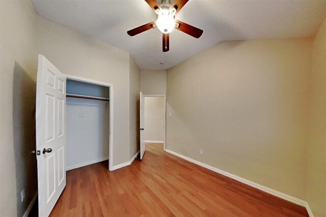 unfurnished bedroom with ceiling fan, a closet, lofted ceiling, and hardwood / wood-style flooring