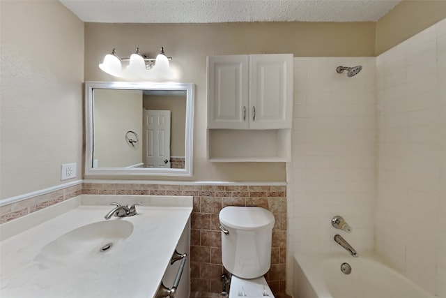 bathroom with vanity, a textured ceiling, tiled shower / bath combo, and tile walls