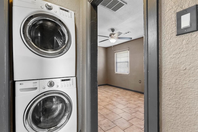 laundry area with ceiling fan, a textured ceiling, and stacked washer and clothes dryer