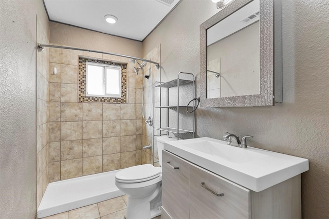 bathroom with tile patterned floors, vanity, toilet, and a tile shower