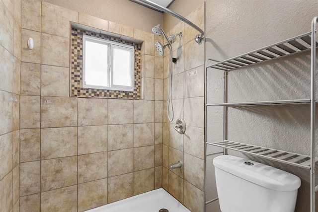 bathroom with a tile shower and toilet