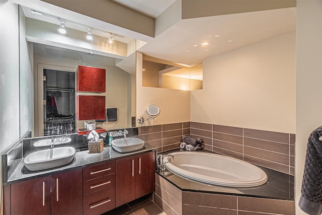 bathroom with vanity, tiled tub, and tile patterned flooring