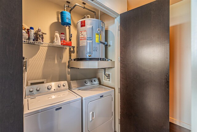 clothes washing area with washer and clothes dryer, wood-type flooring, and electric water heater