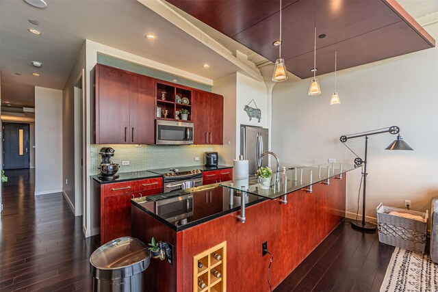 kitchen with a kitchen bar, appliances with stainless steel finishes, dark hardwood / wood-style flooring, and tasteful backsplash