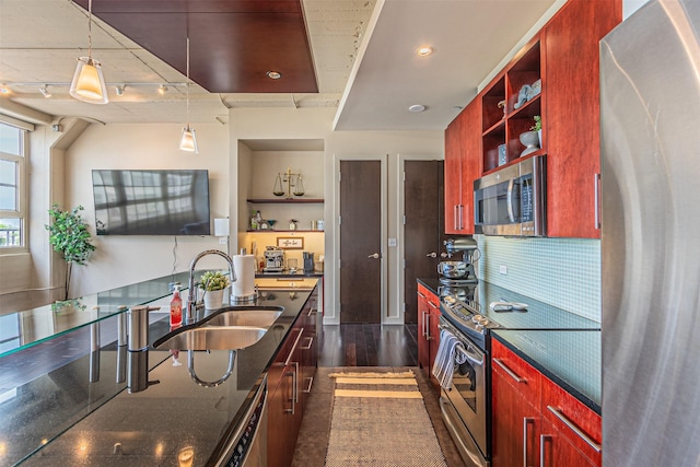 kitchen featuring appliances with stainless steel finishes, dark hardwood / wood-style flooring, sink, decorative light fixtures, and dark stone countertops